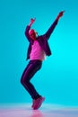 Full-length portrait of young bald man with moustache in casual clothes dancing against blue studio background in neon Royalty Free Stock Photo