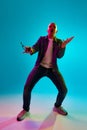 Full-length portrait of young bald man with moustache wearing casual clothes, posing against blue studio background in Royalty Free Stock Photo