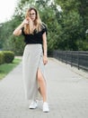 Full length portrait of young beautiful long hair woman wearing black blouse, holding mobile phone at summer green park path backg Royalty Free Stock Photo