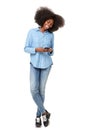 Full length young black woman smiling at mobile phone text message