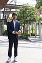 Full length portrait of businessman in trendy formal black suit looking away while standing outdoor near with office. Royalty Free Stock Photo