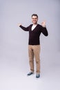 Full length portrait of a young casual man presenting something in the back isolated on gray background. Royalty Free Stock Photo