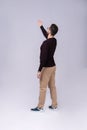 Full length portrait of a young casual man presenting something in the back isolated on gray background. Royalty Free Stock Photo