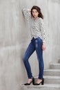 Full length portrait of young fashionable brunette woman practicing model posing outdoors against urban style background of grey c Royalty Free Stock Photo