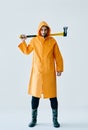 Full length portrait of young handsome man in bright raincoat holding big axe Royalty Free Stock Photo