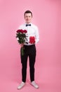 Full length portrait of a young handsome man carrying a flower bouquet and gift box Royalty Free Stock Photo