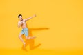 Young happy shirtless Asian man in beach attire jumping in mid-air pointing two fingers at blank space Royalty Free Stock Photo