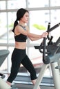 Portrait of young healthy and sporty woman using exercise machine in gym Royalty Free Stock Photo