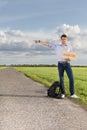 Full length portrait of young man with anywhere sign gesturing on countryside