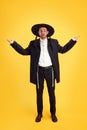 Full length portrait of young man dressed formal suit confusedly looks at camera and spread arms against vivid yellow Royalty Free Stock Photo