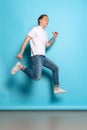 Full-length portrait of young man, student in casual style outfit jumping  on blue background. Human emotions Royalty Free Stock Photo