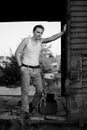 Full-length portrait of young man, wearing grey pants, white top, standing inside old railway carriage, leaning on doors. Black Royalty Free Stock Photo