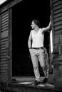 Full-length portrait of young man, wearing grey pants, white top, standing inside old railway carriage, leaning on doors. Black Royalty Free Stock Photo