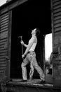 Full-length portrait of young man, wearing grey pants, white top, standing inside old railway carriage, leaning on doors. Black Royalty Free Stock Photo