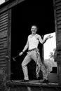 Full-length portrait of young man, wearing grey pants, white top, standing inside old railway carriage, leaning on doors. Black Royalty Free Stock Photo