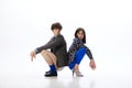 Full length portrait of young people, beloved couple squat back to back dressed in stylish, bright and fancy outfits. Royalty Free Stock Photo
