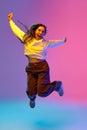 Full-length portrait of young positive woman jumping of joy against gradient purple-blue-pink background. Concept of Royalty Free Stock Photo