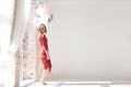 A full-length portrait of young pretty brunette woman with short curly hair, wearing red dress, doing dancing posing, holding pink Royalty Free Stock Photo