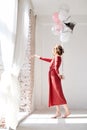 A full-length portrait of young pretty brunette woman with short curly hair, wearing red dress, doing dancing posing, holding pink Royalty Free Stock Photo