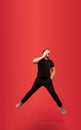 Full length portrait of young successfull high jumping man gesturing  on red studio background Royalty Free Stock Photo