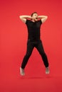 Full length portrait of young successfull high jumping man gesturing  on red studio background Royalty Free Stock Photo