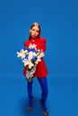 Full-length portrait of young weird girl in unusual, strange, variegated retro clothes and posing with flower bunch Royalty Free Stock Photo