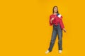 Full-length portrait of young woman with the flag of France in her hands. Yellow background. Learn French. Immigration to France