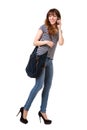 Young woman walking against white background with mobile phone and purse Royalty Free Stock Photo