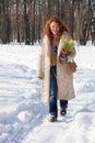 Joyful red haired woman walking along winter footpath
