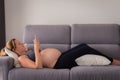 Full length of a pregnant woman lying on the sofa using her smartphone Royalty Free Stock Photo