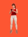 Full length of pretty young woman with mobile phone while jumping Royalty Free Stock Photo