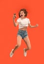 Full length of pretty young woman with mobile phone while jumping Royalty Free Stock Photo
