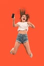 Full length of pretty young woman with mobile phone while jumping Royalty Free Stock Photo