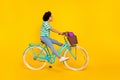 Full length profile photo of impressed young lady ride bicycle wear t-shirt jeans shoes bag isolated on yellow Royalty Free Stock Photo