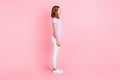 Full length profile side photo of serious charming little girl wear casual outfit isolated on pastel pink color