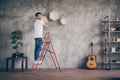 Full length profile view photo of mixed race guy installing wall shelf standing stepladder repair of new flat handmade