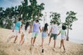 Full length rear behind portrait of group positive excited people hold hands running sand beach outdoors Royalty Free Stock Photo