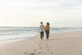 Full length rear view of biracial couple walking while leaving footprints on sand at beach Royalty Free Stock Photo