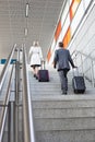 Full length rear view of businesspeople with luggage moving upstairs in railroad station