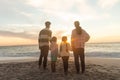 Full length rear view of multiracial family standing on shore at beach during sunset Royalty Free Stock Photo