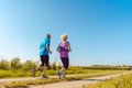 Two healthy senior people jogging on a country road in summer