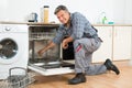 Repairman Repairing Dishwasher With Screwdriver In Kitchen Royalty Free Stock Photo