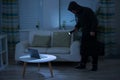 Robber Holding Flashlight Over Laptop At Home