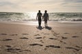 Full length of senior multiracial couple holding hands walking at beach with footprints on sunny day Royalty Free Stock Photo