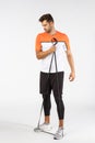 Full-length serious-looking handsome masculine athlete, secure resistance loop under feet, stretch equipment with one