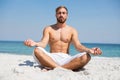 Full length of shirtless man meditating at beach Royalty Free Stock Photo