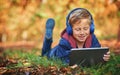 Enjoying his time outdoors. Full length shot of an adorable little boy using a tablet while sitting outdoors during Royalty Free Stock Photo