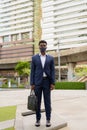 Full length shot of African businessman outdoors in city wearing face mask Royalty Free Stock Photo