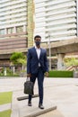 Full length shot of African businessman walking outdoors in city wearing face mask Royalty Free Stock Photo