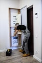 Full length shot of aged electrician, repairman in uniform working, examining, testing equipment in fuse box. Repair